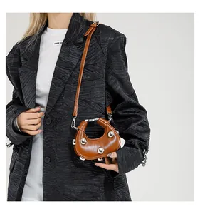 Side view of a brown leather crescent bag with silver stud details on a model