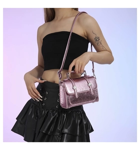 Detail of pink metallic handbag with pleated texture and decorative buckle straps
