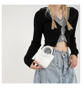 Nahaufnahme einer mini weißen Leder-Beuteltasche mit silberner Kette an einem Model
