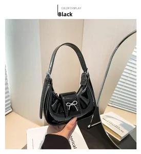 Detail of black patent leather hobo bag featuring a silver metal bow decoration