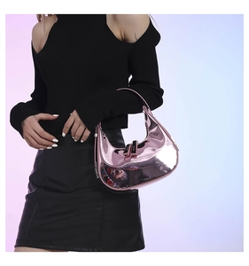 Macro detail of glossy metallic pink crescent hobo bag with reflective mirror finish