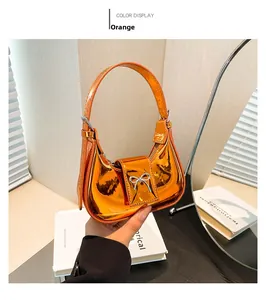 Close-up of orange metallic patent leather mini handbag with silver bow detail