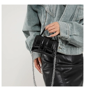 Détail du mini sac bandoulière en cuir verni noir brillant avec chaîne argentée
