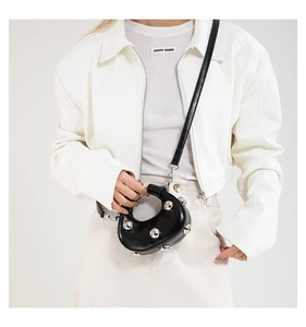 Detail view of mini black leather saddle bag with silver studs and detachable strap