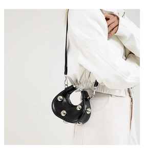 Close-up of black crescent dumpling bag with silver studs and detachable shoulder strap