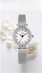 Detail of silver mesh watch featuring colorful crystal markers and floral engraved bezel