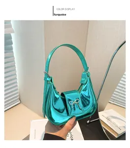Detail view of mini green metallic handbag with a silver bow and sleek half-moon shape