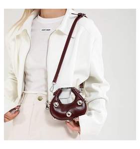 Detail view of burgundy leather crossbody bag with oversized silver studs and zip closure