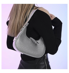 Detail of silver rhinestone crescent bag worn on shoulder showing shimmering texture