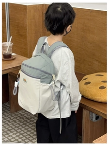 Detail of kids backpack featuring two-tone grey and white nylon with side drawstring pocket