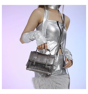 Close-up of metallic silver messenger bag with crackle texture on model's outfit