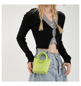 Neongrüne Mini-Beuteltasche mit silberner Kette im modischen Styling am Modell