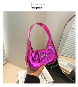 Close-up of fuchsia patent leather handbag featuring a silver metallic bow detail