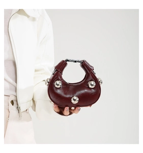 Detail of burgundy micro dumpling bag with silver rivets and metal lock handle