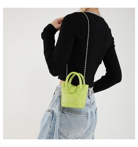 Detail der neongrünen Mini-Beuteltasche mit silberner Kette und Lederstruktur