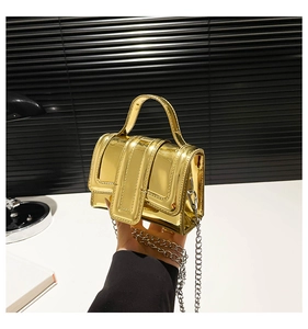 Détail macro du mini sac à main doré brillant avec bandoulière chaîne et effet miroir