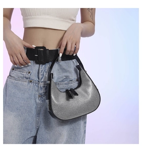 Detailed view of silver sequin crescent bag with black leather trim and zipper accents