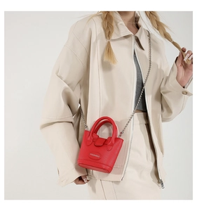 Rote Mini-Eimertasche mit Litschi-Struktur und silberner Kette am Modell getragen