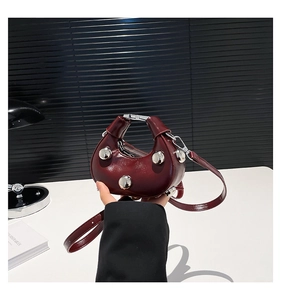 Detail view of burgundy crescent handbag with silver studs and smooth leather texture