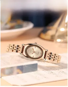 Close-up van roségoudkleurig tonneau quartzhorloge met mesh band op bladmuziek