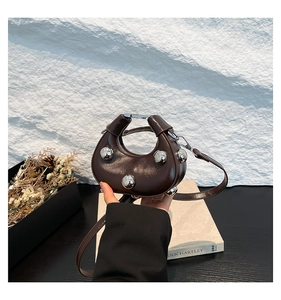 Detail of dark brown leather crescent bag with metallic studs and fine strap