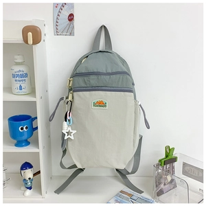 Detail view of the canvas backpack showing front zipper pockets and star charm accessory
