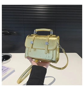 Detail of a shiny gold metallic mini crossbody bag with a silver round buckle