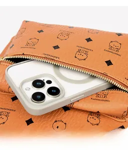 Detail der orangefarbenen Ledertasche mit Bärenmuster und einem Smartphone darin