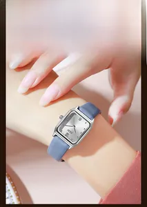 Close-up of a vintage square silver watch with a fog blue leather strap on a wrist
