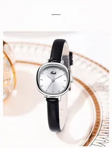 Detail view of a minimalist quartz watch with a silver sunray dial and black leather strap