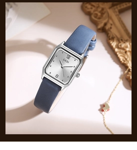 Detail of square silver quartz watch with navy leather strap and heart necklace decor