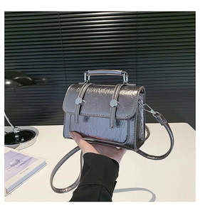 Detail of silver metallic textured crossbody bag with decorative straps and buckles