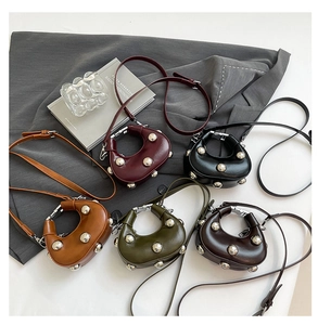 Detailed overhead view of five rivet dumpling bags in matte leather on gray fabric