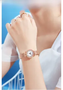 Detail of rose gold watch with woven metal strap and colorful rhinestone markers