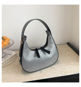 Detailed close-up of silver glitter hobo bag with black patent leather trim and dual zippers