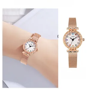 Detail of rose gold mesh strap watch with colorful rhinestone markers and white dial