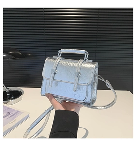 Detail of silver metallic messenger bag with vintage crinkled texture and buckle straps