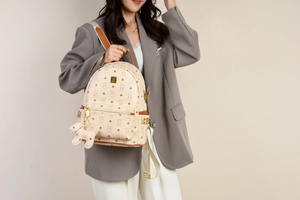 Detail eines cremefarbenen Rucksacks mit Bärenprint, Goldbeschlägen und Nieten