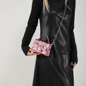 Mini sac à main rose métallisé avec chaîne argentée sur une robe noire