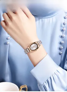 Close-up van elegant tweekleurig horloge met champagne ovale wijzerplaat om de pols