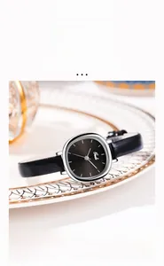 Detail of vintage round watch with black leather strap on decorative porcelain plate