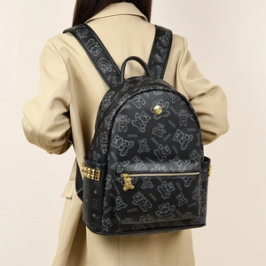 Détail d'un grand sac à dos noir avec imprimé ours et boucles dorées porté par un mannequin