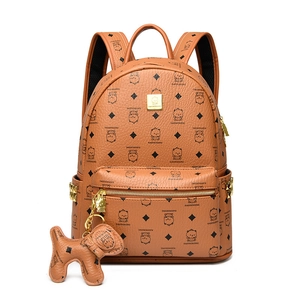 Détail d'un sac à dos marron avec imprimés ours, motifs losanges et breloque chien