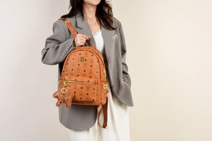 Detail eines braunen Mini-Rucksacks mit Bärenprint und passendem Bärenanhänger am Model
