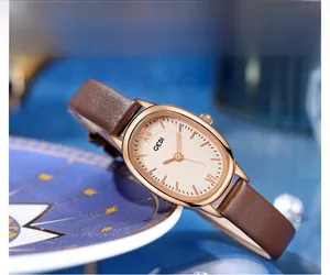 Macro shot of oval rose gold watch case with brown leather strap on a blue background