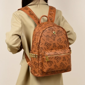 Détail du sac à dos marron imprimé ours avec clous dorés et texture cuir sur un mannequin