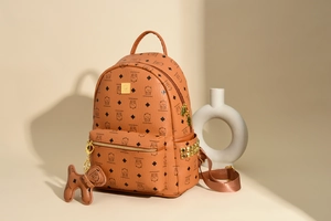 Detail eines braunen PU-Lederrucksacks mit Bärenmuster und goldenen Nietenbesatz
