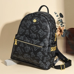 Détail du sac à dos noir avec rivets dorés et imprimé d'ours sur texture grainée
