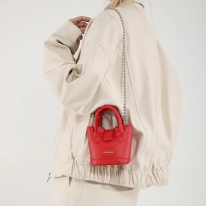 Schicke rote Mini-Beuteltasche mit silberner Kette, getragen von einem Modell im modernen Stil