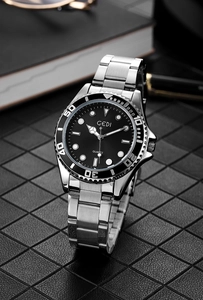 Detail of silver stainless steel business watch with black dial and diver bezel on a desk